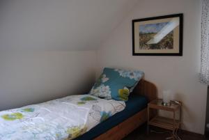 um pequeno quarto com uma cama e uma fotografia na parede em Haus Wiesengrund em Rauhenebrach