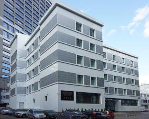 Brosko Hotel Arbat في موسكو: مبنى أبيض طويل وبه سيارات متوقفة أمامه