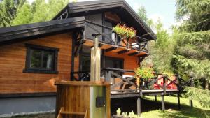 a log cabin with a balcony with flowers on it at Chalet Račkova dolina in Pribylina