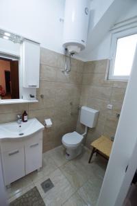 a bathroom with a toilet and a sink and a window at Apartman Oaza in Trebinje