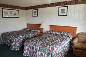 a hotel room with two beds and a chair at Gateway Inn Fairfield in Fairfield