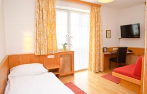 um quarto com uma cama, uma secretária e uma televisão em Hotel Gasthof König em Kremsmünster