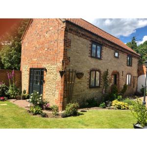a brick house in a yard with a grass yard at Church View Cottage, Ewerby in Sleaford