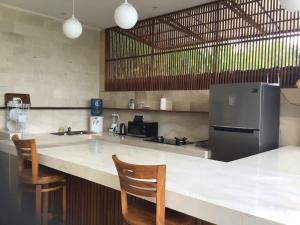 una cucina con bancone, 2 sedie e frigorifero di Villa Tenang ad Ubud