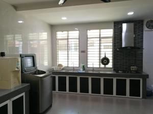 a kitchen with a sink and a tv and windows at EJ Guesthouse in Cukai