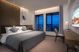 Un dormitorio con una cama, un escritorio y ventanas. en Citadines Songshan Lake Dongguan, en Dongguan