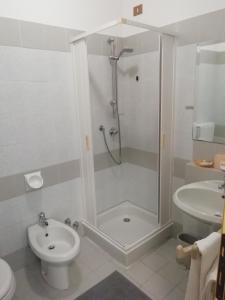 a bathroom with a shower and a toilet and a sink at Hotel Rezia Valtellina in Morbegno