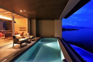 una piscina en una casa con vistas al agua en AMANE resort SEIKAI, en Beppu