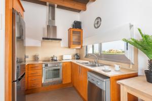 una cocina con armarios de madera y electrodomésticos de acero inoxidable en Villa Marta, en Es Mercadal