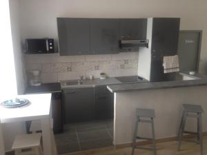 a kitchen with a sink and a counter with two stools at Gîte Emma in Santo-Pietro-di-Tenda