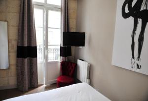 - une chambre avec un lit, une chaise rouge et une fenêtre dans l'établissement Burdigala Homes - Appart Porte Basse, à Bordeaux