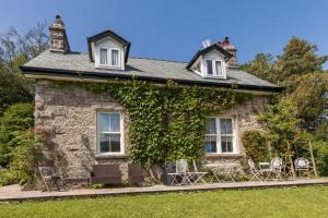 Una casa de piedra con hiedra a un lado. en Woodhaven - Luxury 4 bedroom rural retreat with hot tub near to Lake District en Grange Over Sands