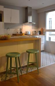 a kitchen with two green stools next to a counter at Burdigala Homes - Appart de Lalande in Bordeaux