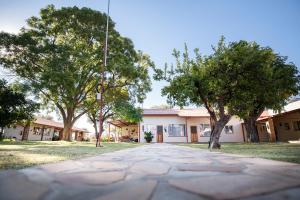 a walkway in front of a building with trees at Dornhuegel Guest Farm in Groutfontein