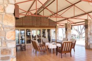 uma sala de jantar com mesas e cadeiras e uma parede de pedra em Dornhuegel Guest Farm em Grootfontein