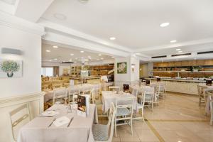 プラヤ・デ・パルマにあるHotel Metropolitan Playa 3 Supの白いテーブルと椅子、カウンター付きのレストラン