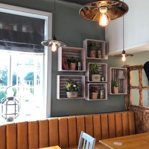 a dining room with a bench and potted plants on the wall at Green Lodge, Wirral by Marston's Inns in Hoylake