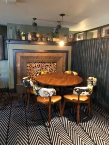 a table and chairs in a room with a fireplace at Green Lodge, Wirral by Marston's Inns in Hoylake