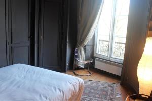 een slaapkamer met een bed, een raam en een stoel bij Burdigala Homes - Appart Clemenceau in Bordeaux
