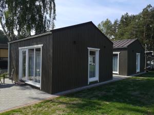 a black house with white windows on a yard at Delta Plius in Šventoji