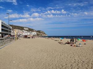 a group of people sitting on a beach at Home By The Sea in Sesimbra