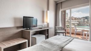um quarto de hotel com uma cama, uma televisão e uma varanda em Be Live Experience Costa Palma em Palma de Maiorca