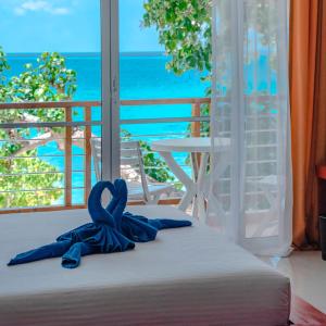 łóżko z niebieską wstążką przed oknem w obiekcie Athiri Beach Maldives w mieście Dhigurah