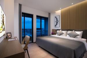 a bedroom with a bed and a desk and windows at Citadines Songshan Lake Dongguan in Dongguan