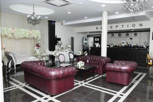 a salon with red leather couches and a table and chairs at Hotel Emi in Strumica