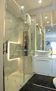 a bathroom with a glass shower and a sink at Blue Velvet Premium Apartments II in Toruń