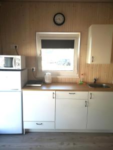 uma cozinha com armários brancos e uma janela em Delta Plius em Šventoji