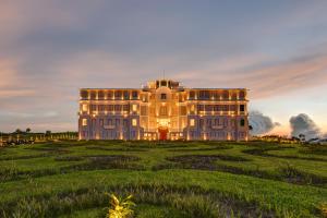 a large house in a field with a sunset at Le Bokor Palace in Kampot