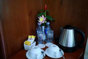 a table with two bottles and a tea kettle and a flower at Chheng Residence in Siem Reap