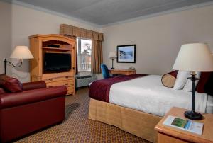 a hotel room with a bed and a chair at Cherry Tree Inn & Suites in Traverse City