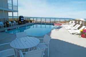 eine Terrasse mit einem Tisch und Stühlen sowie einem Pool in der Unterkunft Cherry Tree Inn & Suites in Traverse City