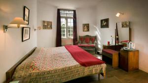 a bedroom with a bed and a chair in it at Neemrana's Wallwood Garden in Coonoor