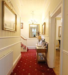 pasillo con alfombra roja, mesa y espejo en The Daylesford Guest House, en Torquay