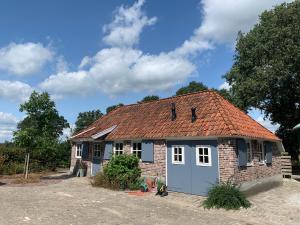 een klein bakstenen huis met een blauwe garage bij Erve Feenstra in Lochem