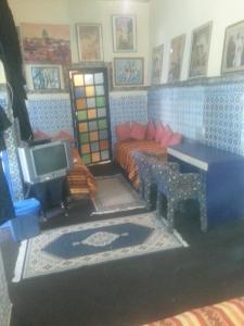 ein Wohnzimmer mit einem Bett und einem TV in der Unterkunft RIAD DAR KADER chambre saumon in Marrakesch