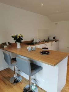 a kitchen with a wooden counter with two bar stools at Couples Country Escape includes Private Indoor Pool and Hot tub in North Wales in Bagilt