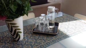une table en verre avec un plateau avec des verres et un vase dans l'établissement Apartment Leśniczówka, à Radom