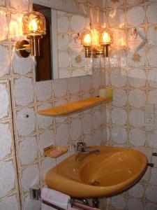une salle de bain avec un lavabo, un miroir et des lumières dans l'établissement Adieu Alltag: Pension Oesterle im Schwarzwald, à Schönmünzach