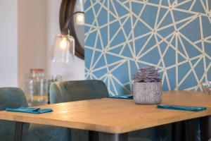 a wooden table with green chairs and a blue wall at Hôtel Relais Acropolis Nice in Nice
