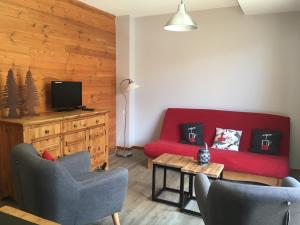 a living room with a red couch and a table at Les Balcons de Vaujany in Vaujany