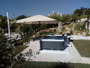 einen Pool mit einem Sonnenschirm, einem Stuhl und einem Tisch in der Unterkunft Trulli La collinetta in Martina Franca