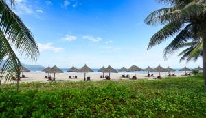 a beach with many straw umbrellas and the ocean at Furama Villas Danang in Danang