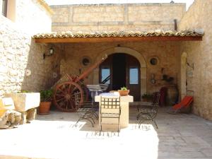 un patio con mesa, sillas y una rueda en Agriturismo Al Casale, en Donnafugata