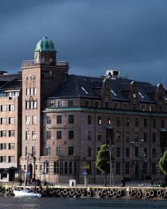 a large building with a clock tower next to the water at Clarion Collection Hotel Havnekontoret in Bergen