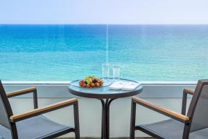 a table with a bowl of fruit and two chairs at Royal Apollonia by Louis Hotels in Limassol
