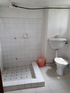 a bathroom with a toilet and a tiled floor at Masaka Backpackers, Tourists Cottage & Campsite in Masaka